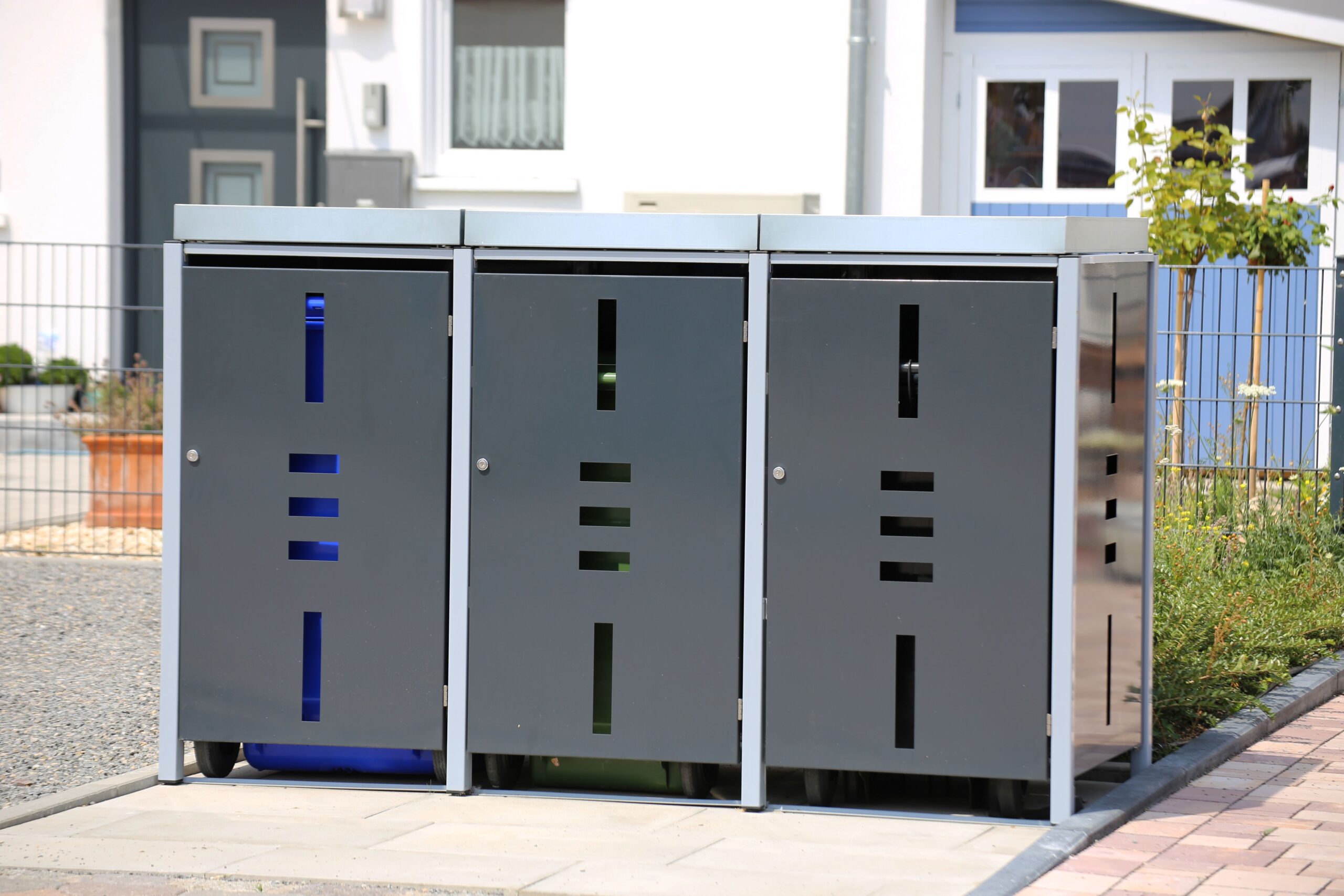 Mülltonnenboxen in modernem Design vor einem Einfamilienhaus als stilvolle Lösung für den Eingangsbereich