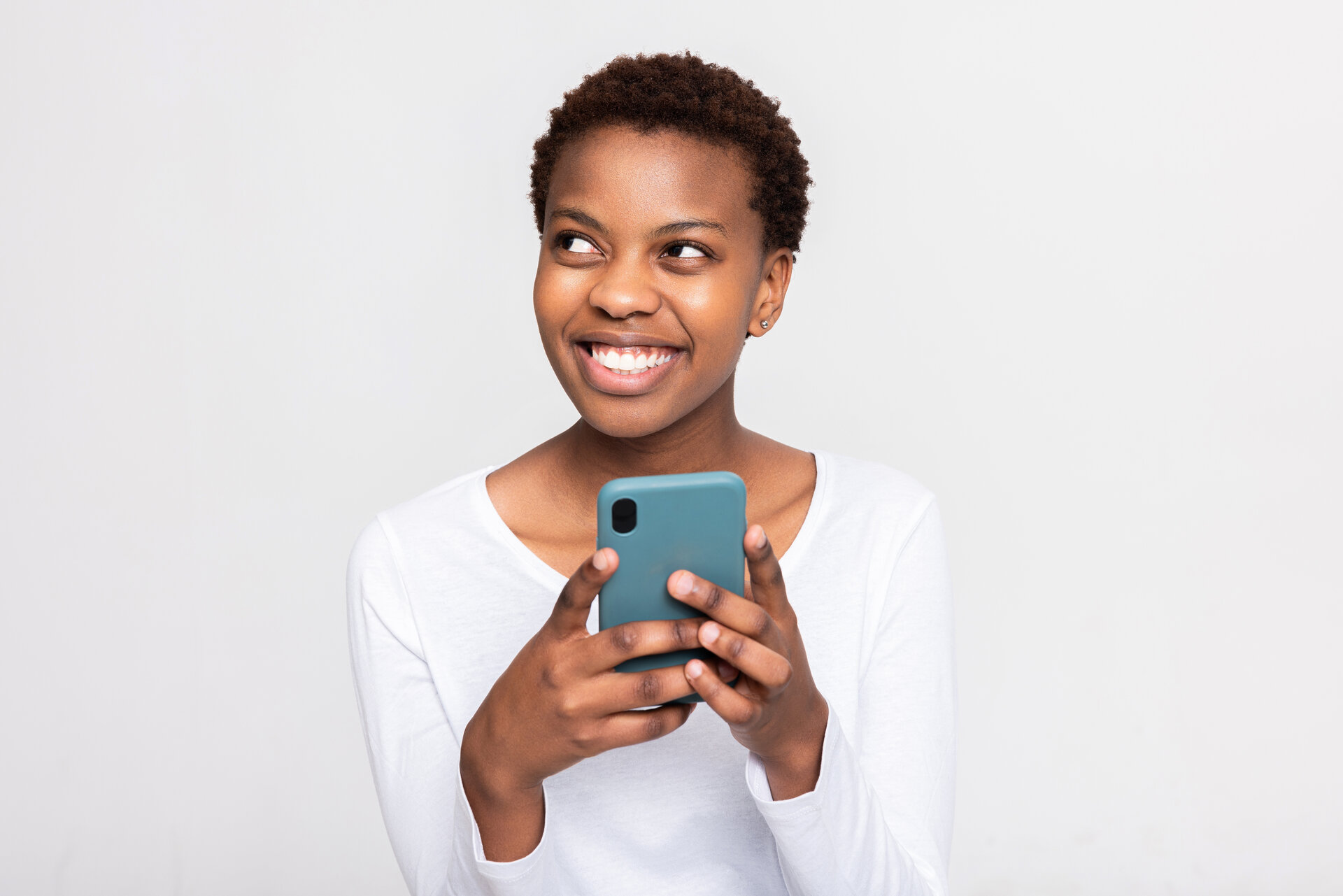 Charmante afrikanische Frau mit Kurzhaarschnitt hält Handy in den Händen Chatten Messaging mit jemandem Freund Freunde Familie hält neue moderne Gerät in den Armen