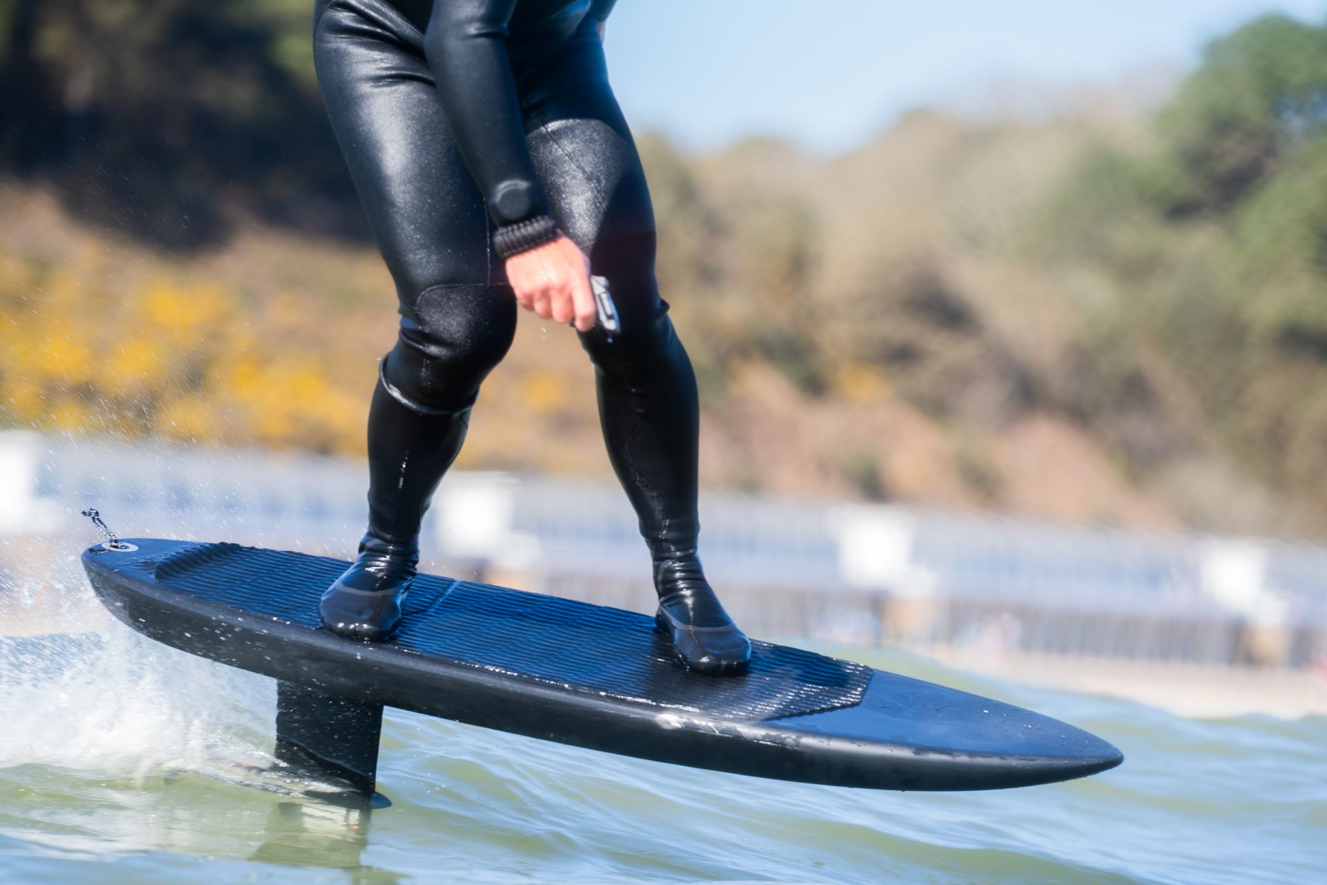 Detailaufnahme eines fahrenden Efoils mit nassem Board und Handsteuerung aus der Nähe
