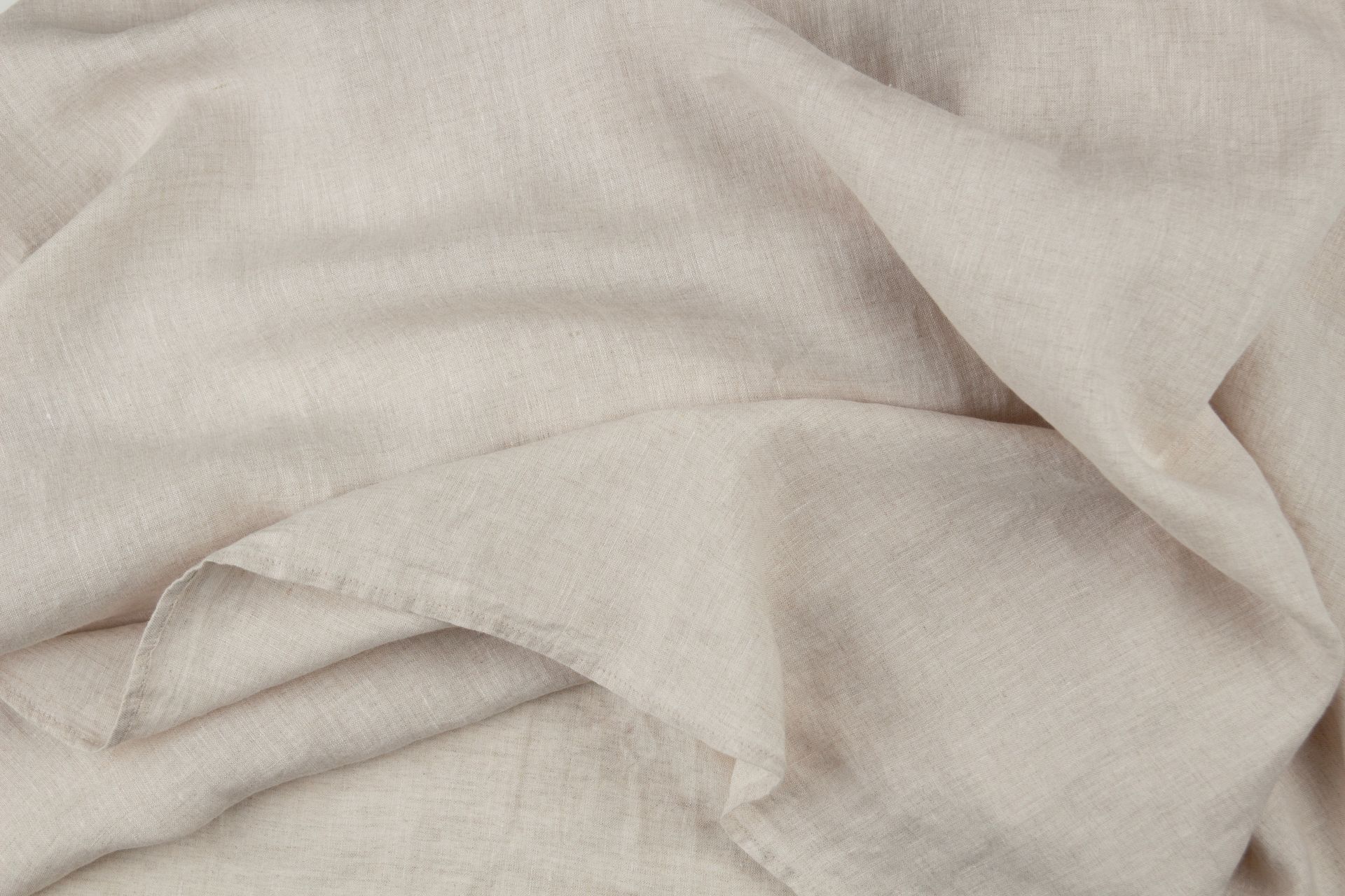 gefalteter-leinenstoff-in-naturfarbe-als-detailaufnahme-fuer-bio-bettwaesche-und-nachhaltige-einrichtung